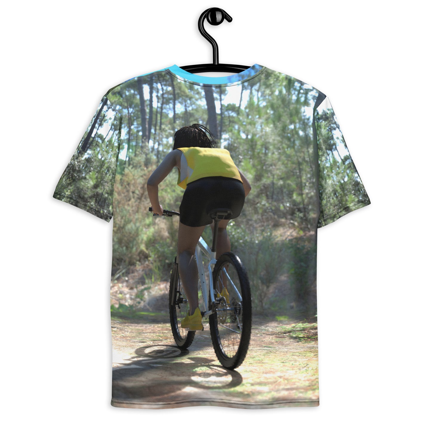 An all over print t-shirt of a black woman riding a bicycle on a trail in the woods.